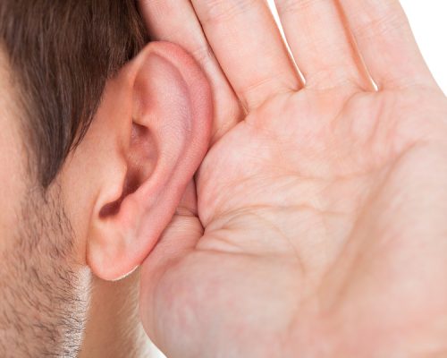 Close-up Of Person Trying To Hear With Hand Over Ear