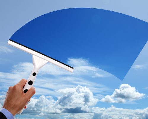 Window cleaner using a squeegee to clear the blue sky above